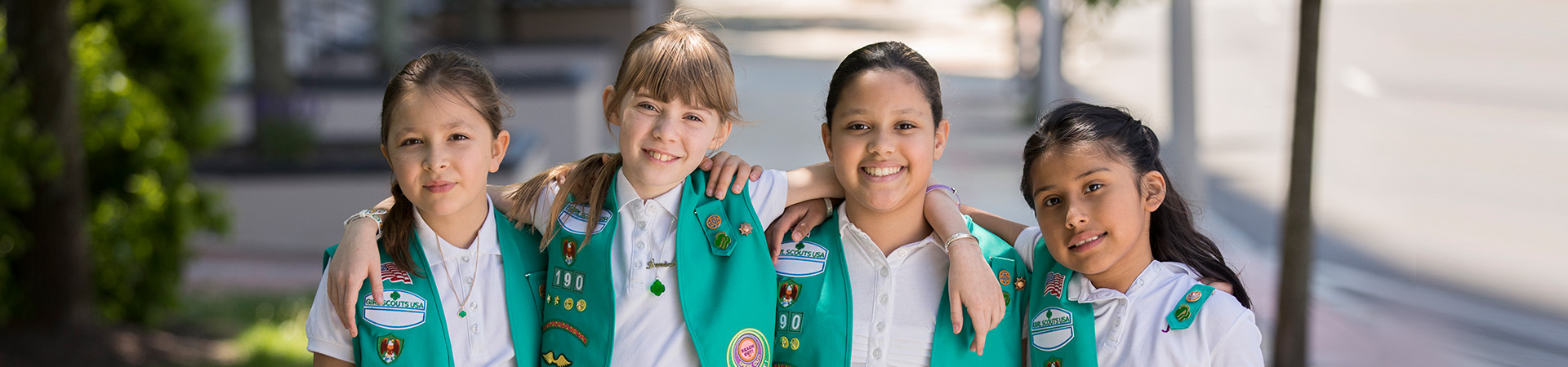  portrait of ambassador girl scout wearing vest and smiling at camera in front of a brick building 